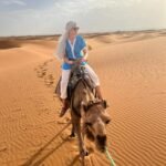 Guest riding a camel during a Morocco tour in the Sahara Desert